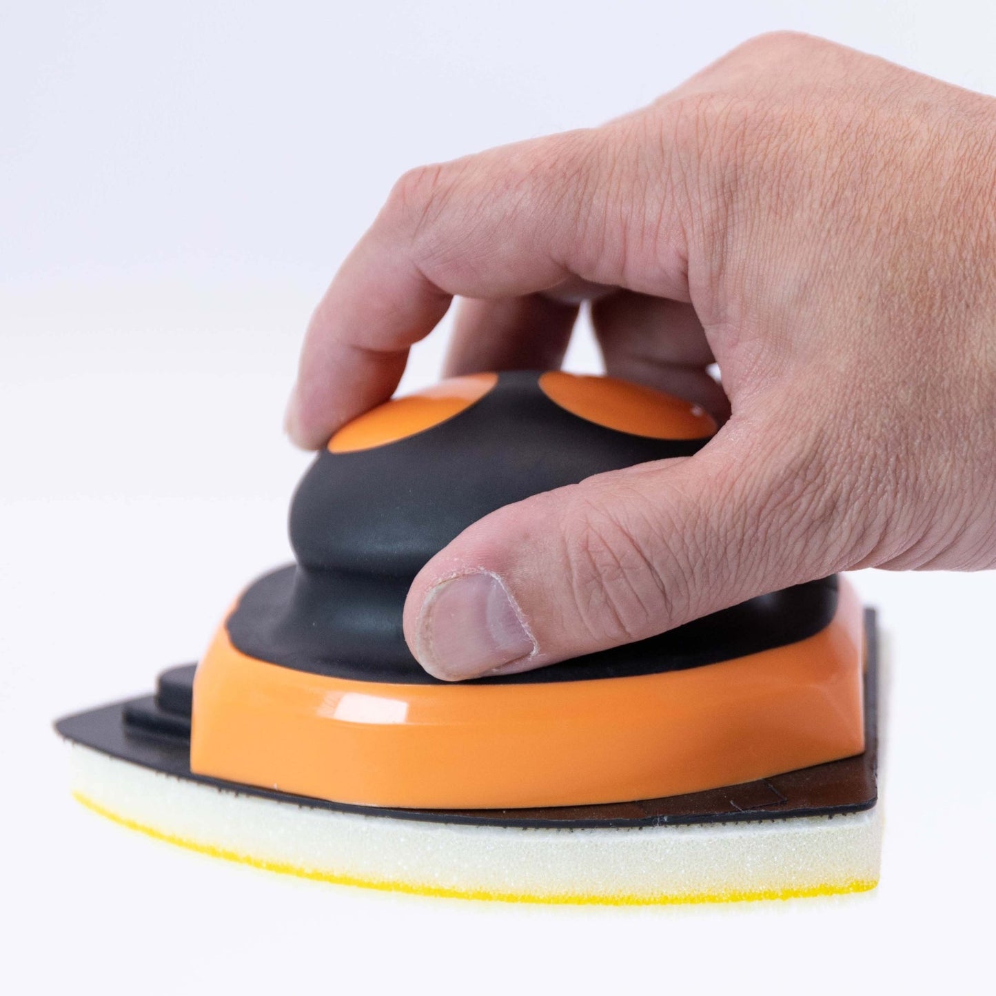 Hand holding an orange and black pad holder against a white background