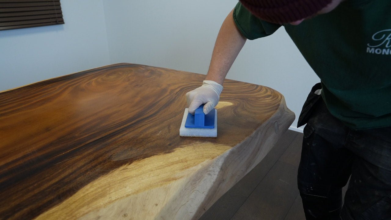 Person applying Rubio Monocoat wood finish to a wooden table using an application pad.