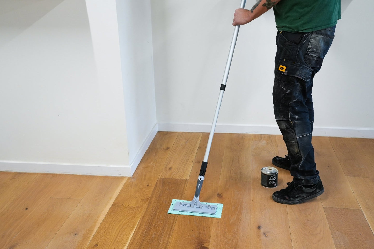 Person cleaning a wooden floor with a tool.